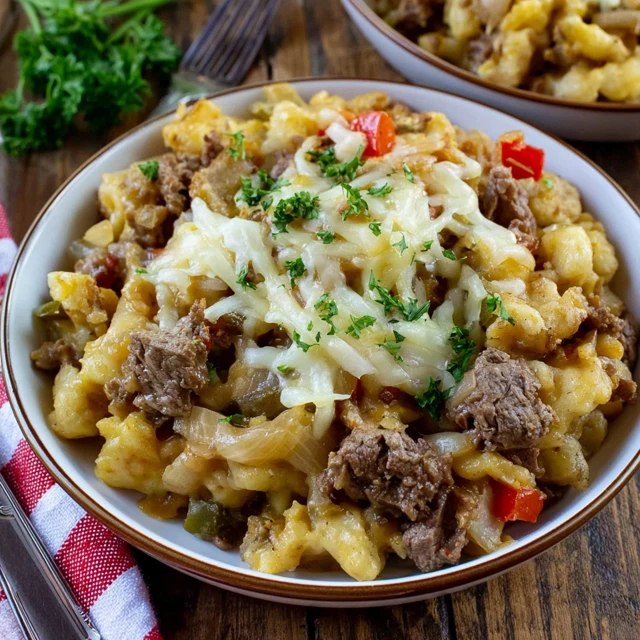 Close-up of a scoop showing crispy tater tots on top, gooey melted cheese and seasoned ground beef underneath