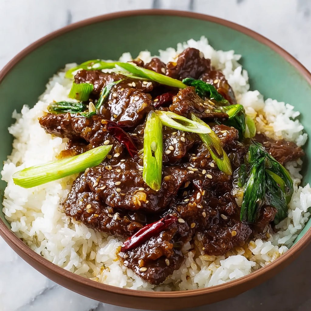 Homemade Mongolian beef served over steamed rice with green onion garnish
