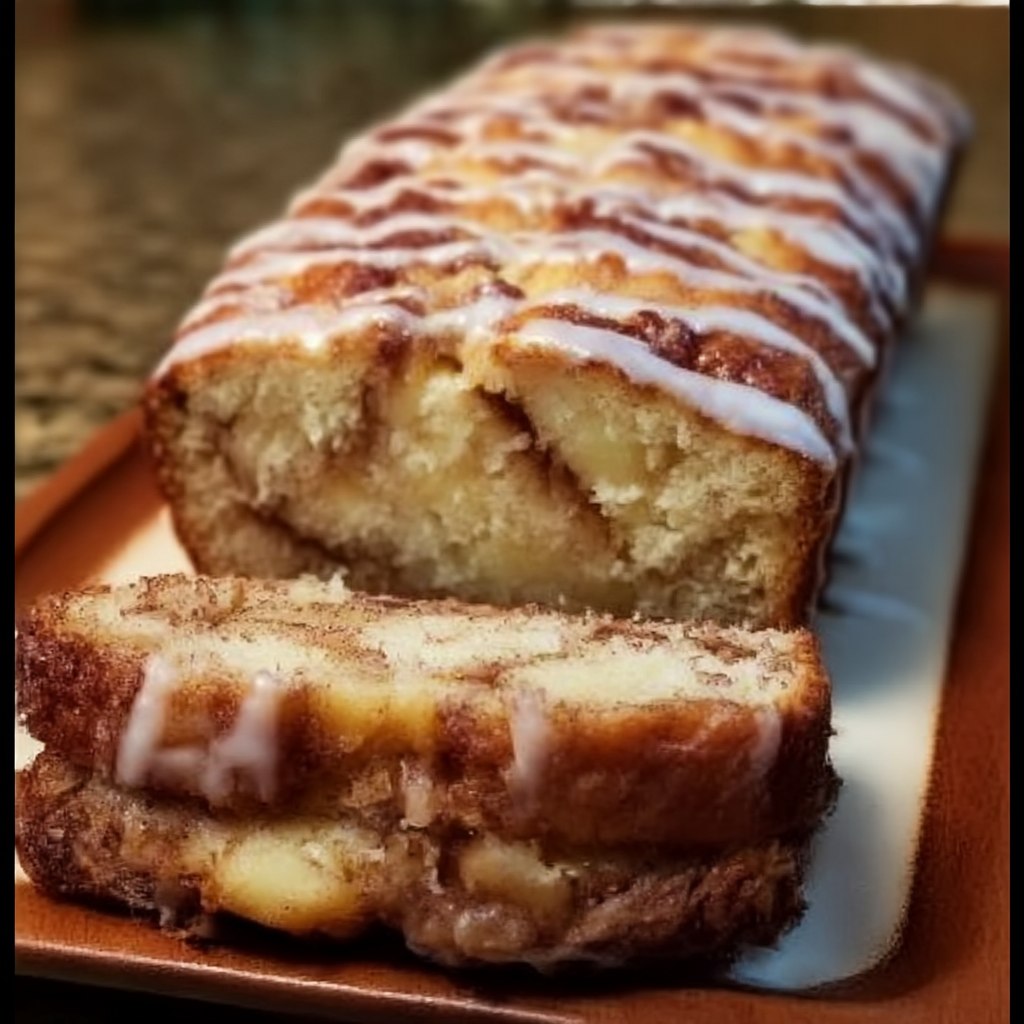 Close-up of cinnamon roll bread slice with thick vanilla icing drips, cinnamon-sugar pinwheel swirl, tender yeast crumb, glistening sugar topping